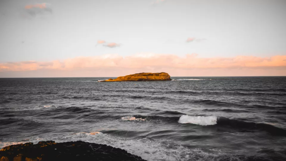 Bild på en lietn ö i ett stormigt hav. Foto: unsplash 